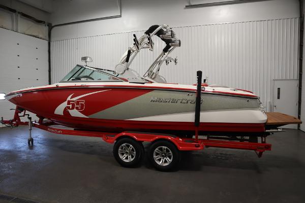 Slide: The Image of 2013 MasterCraft X55 boat in red and white on a trailer in a garage. - 7