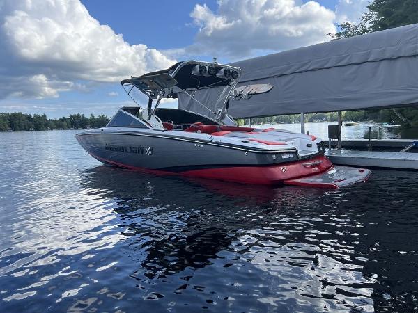 Slide: The Image of 2015 MasterCraft X55 boat docked on a lake under a cloudy sky. - 1