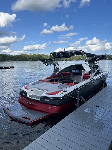 Slide: The Image of 2015 MasterCraft X55 boat docked on a lake under a blue sky. - 2