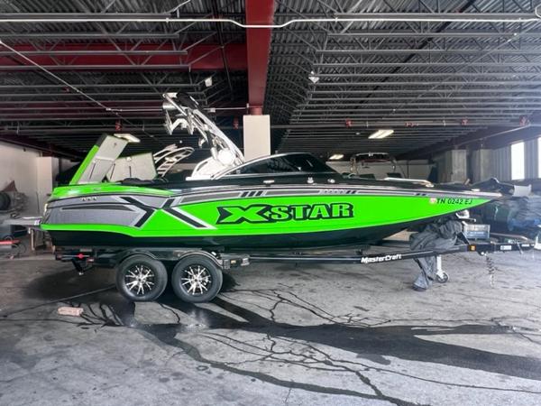 Slide: The Image of 2013 MasterCraft XStar boat in a garage, green and black design. - 1