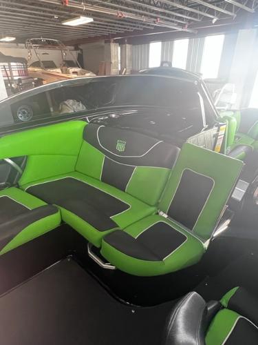 Slide: The Image of 2013 MasterCraft XStar boat with green and black interior in a warehouse. - 16