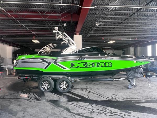 Slide: The Image of 2013 MasterCraft XStar boat in a garage, vibrant green and black design. - 2