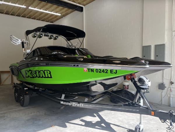 Slide: The Image of 2013 MasterCraft XStar boat in a garage, green and black color scheme. - 3