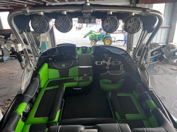 Slide: The Image of 2013 MasterCraft XStar boat interior with green and black seating, tower speakers, and steering console. - 43