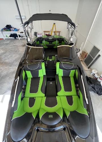 Slide: The Image of 2013 MasterCraft XStar boat with green and black interior in a garage. - 8