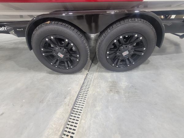 Slide: The Image of 2024 MasterCraft XT24 trailer with black alloy wheels in a showroom. - 24