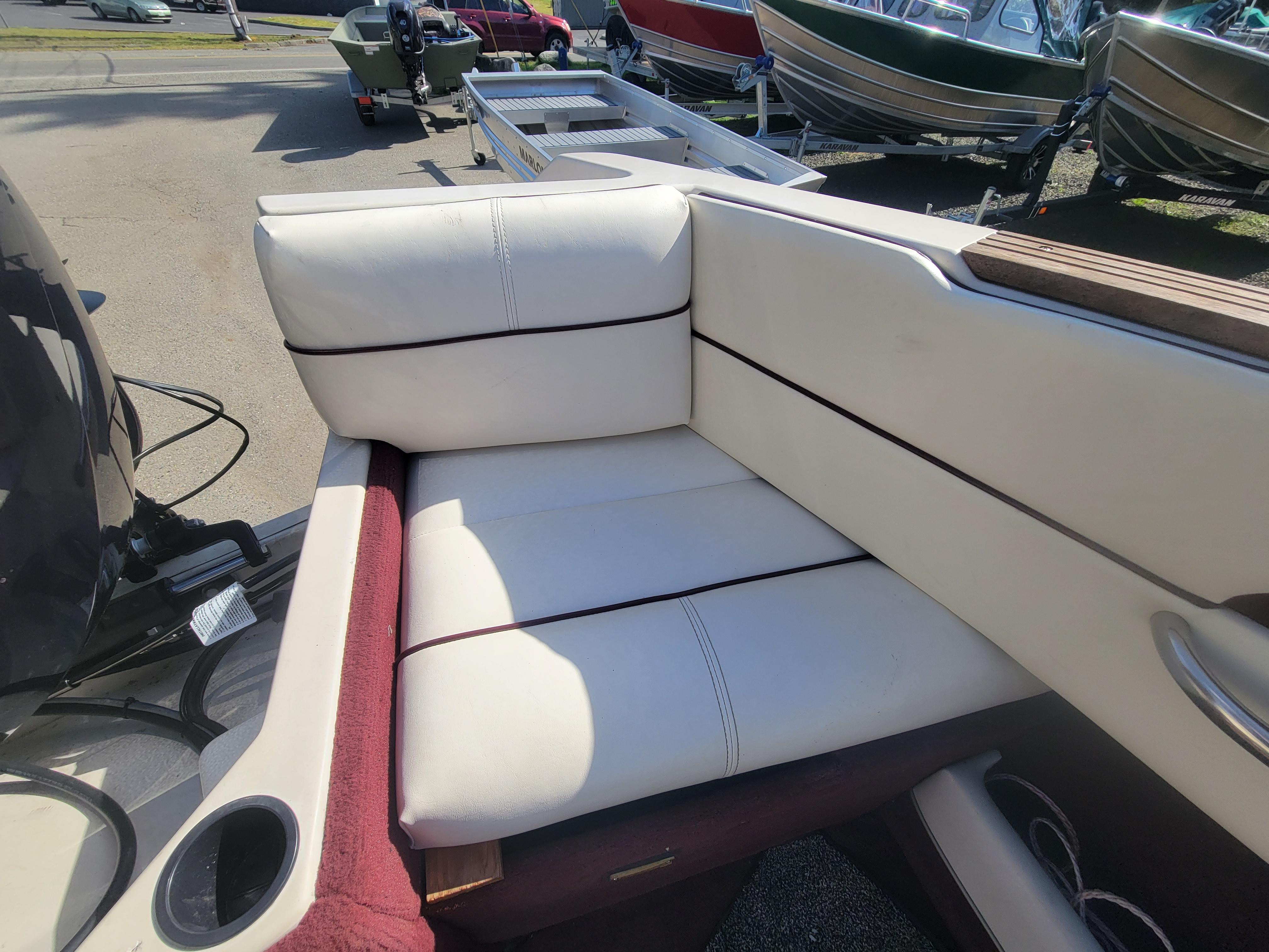 Slide: The Image of White leather seating on a 1991 Maxum 2100 XC boat, with cup holder and motor visible. - 8