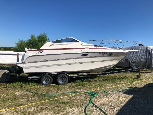 Slide: The Image of 1992 Maxum 2300 SCR boat on trailer, parked outdoors under clear blue sky. - 0
