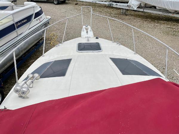 Slide: The Image of 1992 Maxum 2300 SCR boat with red cover, docked alongside other vessels. - 6
