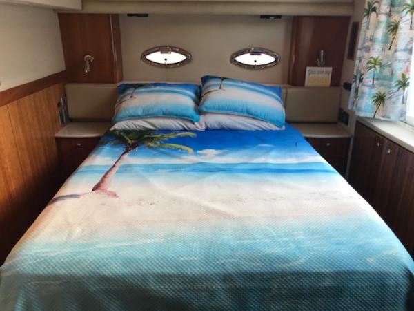 Slide: The Image of 2004 Meridian 459 Motoryacht bedroom with beach-themed bedding and porthole windows. - 30