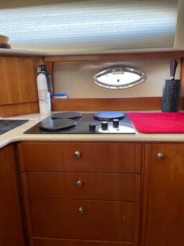 Slide: The Image of 2004 Meridian 459 Motoryacht kitchen with stove, wooden cabinets, and porthole window. - 37