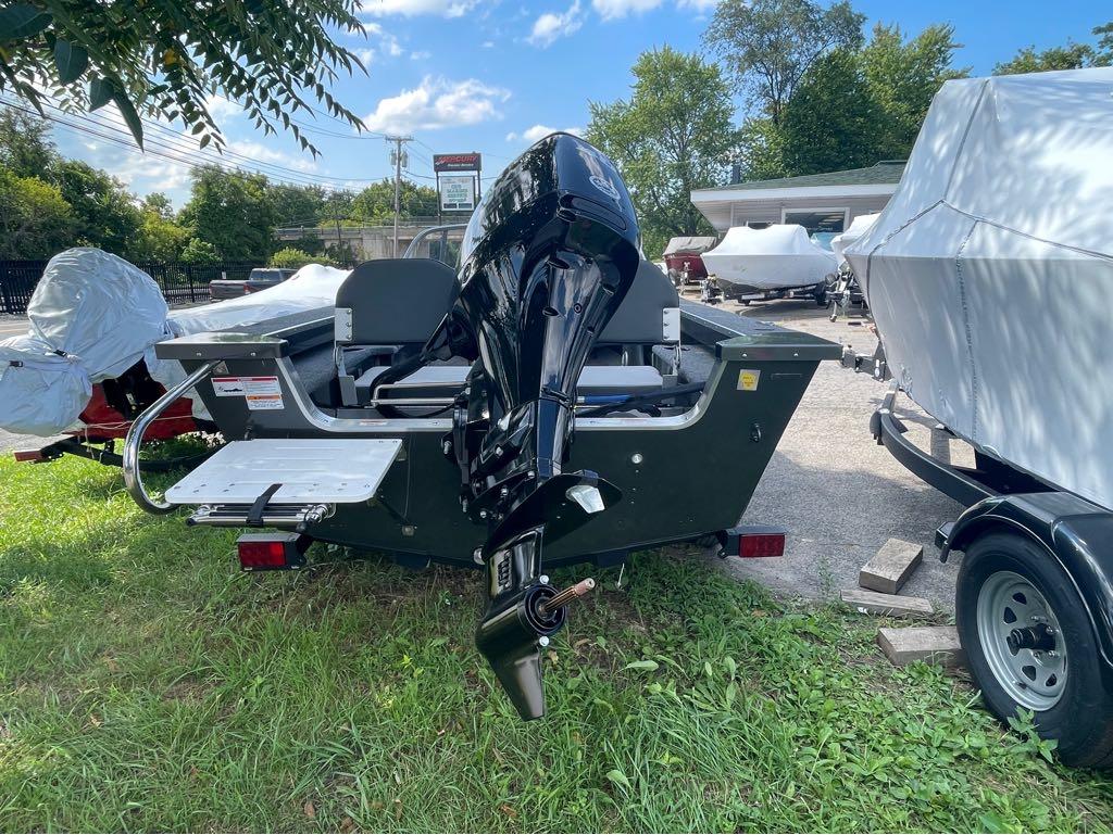 Slide: The Image of 2023 MirroCraft 1628 boat with outboard motor, parked outdoors. - 2