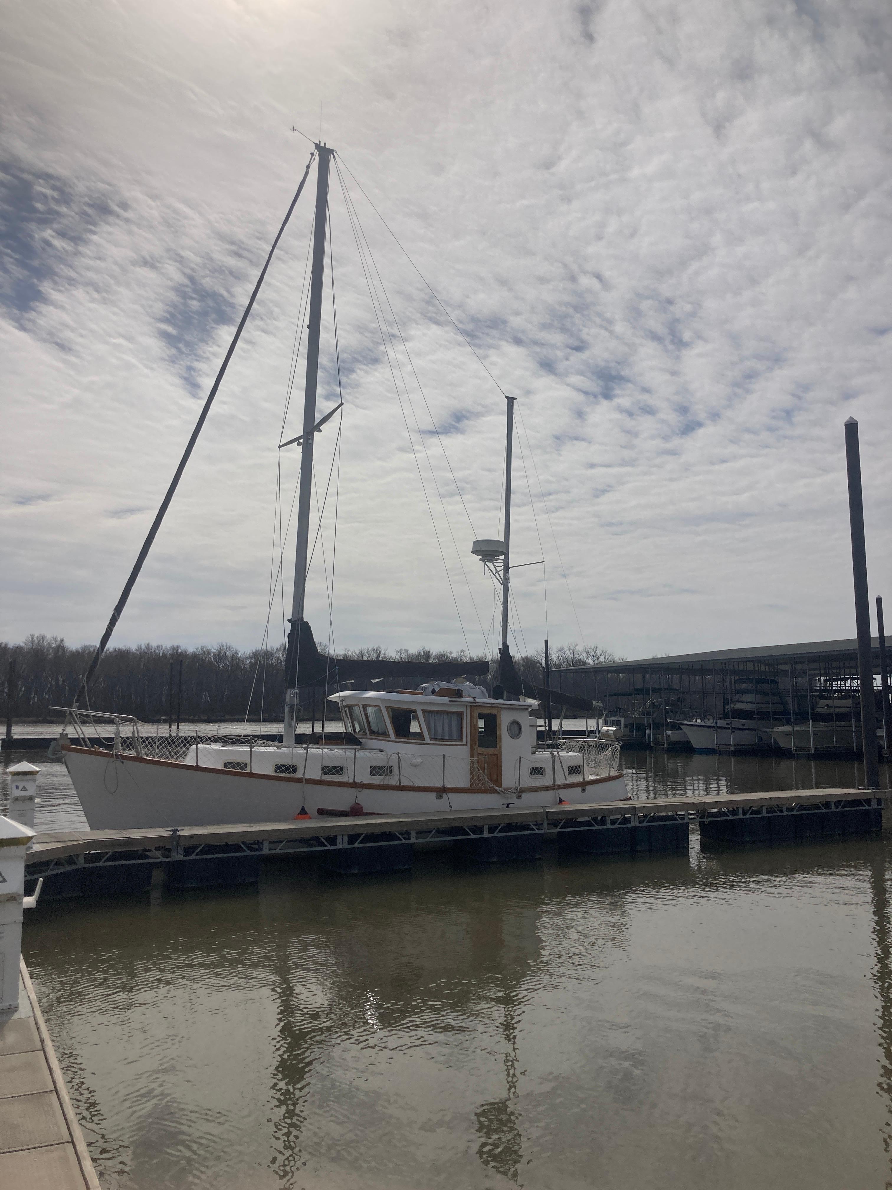 Slide: The Image of 1981 Monk Comfort Monk Motorsailer 38 docked at a marina under a cloudy sky. - 0