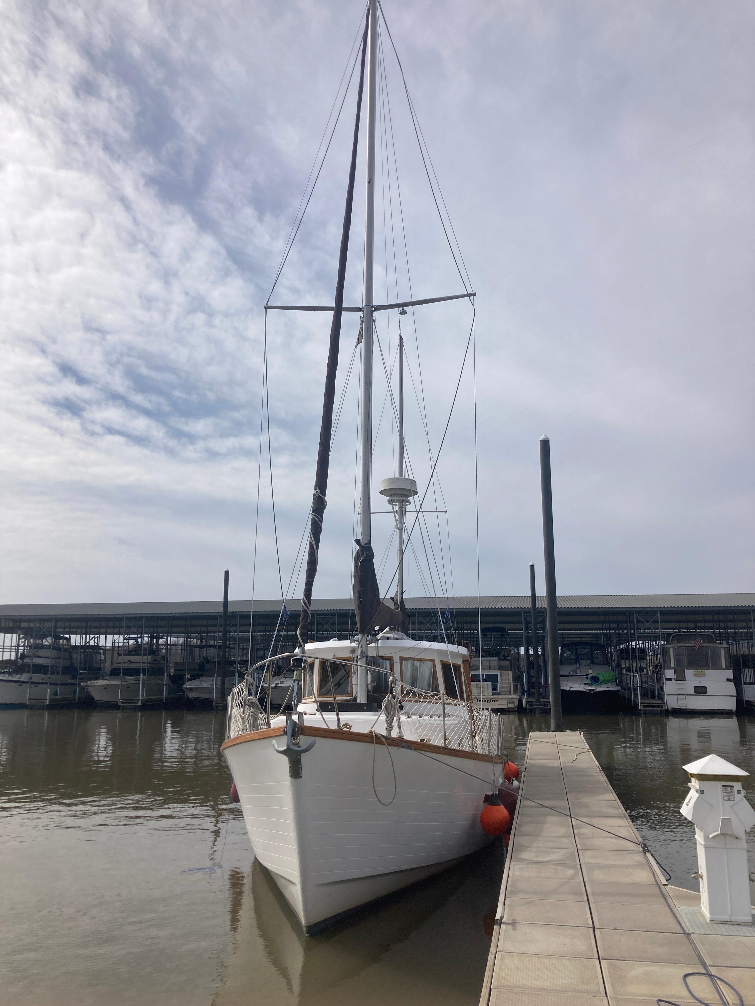 Slide: The Image of 1981 Monk Comfort Monk Motorsailer 38 docked at marina under cloudy sky. - 1