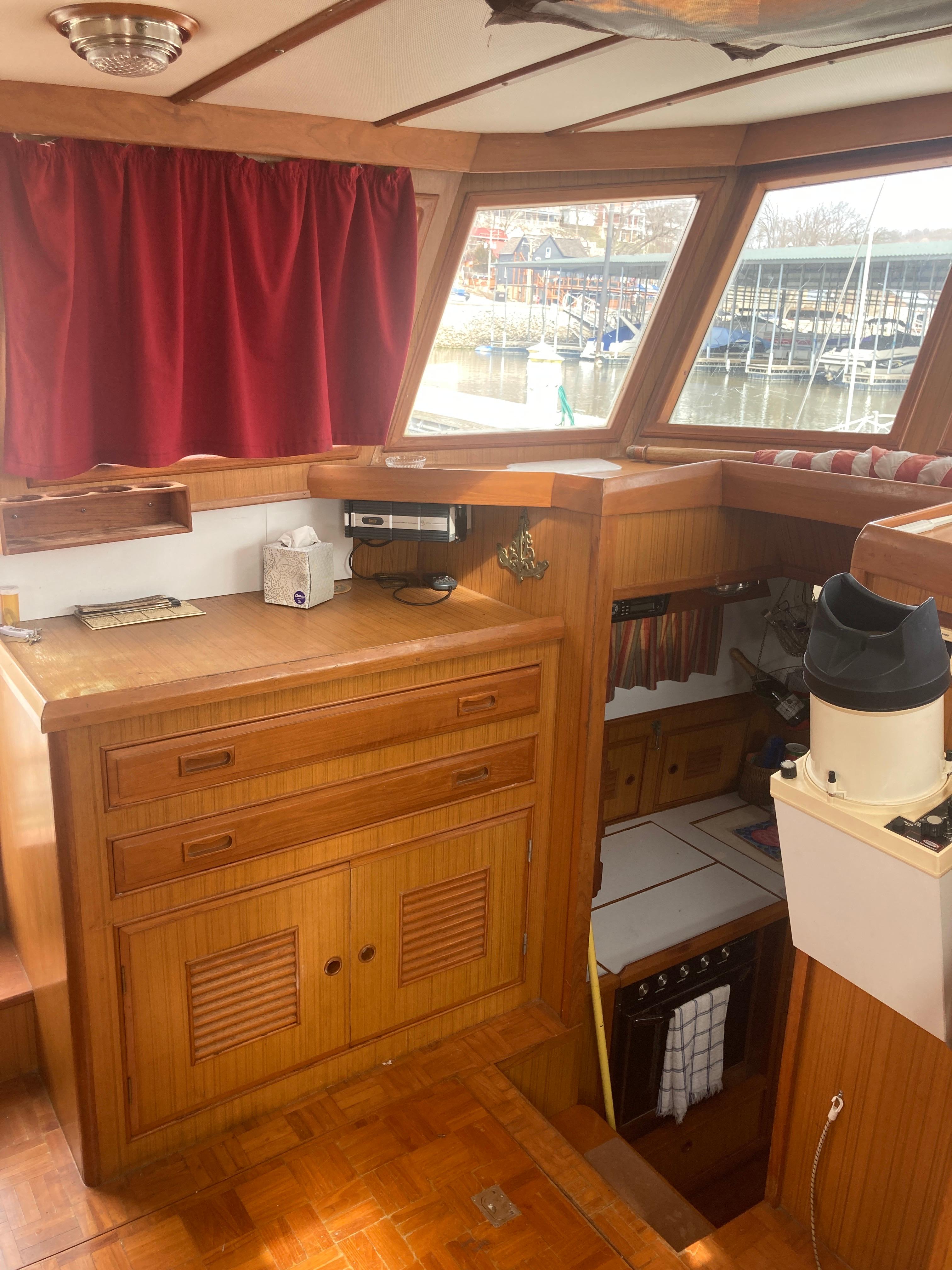 Slide: The Image of Interior of 1981 Monk Comfort Monk Motorsailer 38 with wooden cabinetry and red curtains. - 13