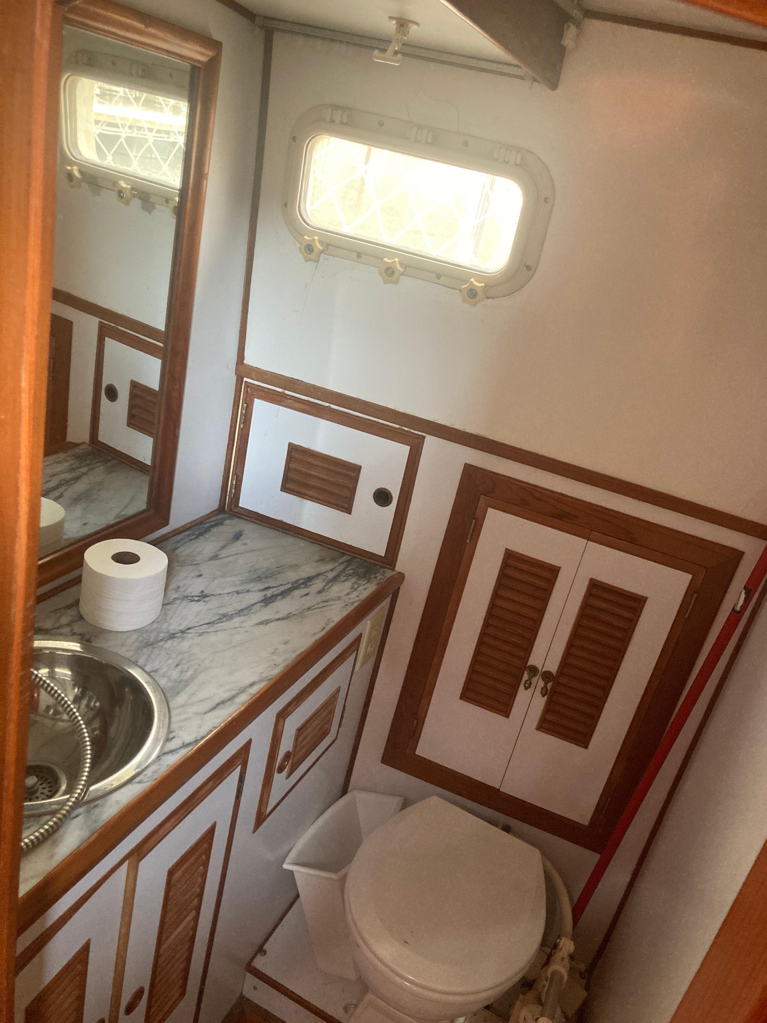 Slide: The Image of 1981 Monk Comfort Monk Motorsailer 38 bathroom with sink, toilet, and storage cabinets. - 7