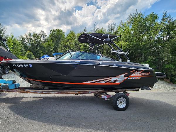 Slide: The Image of 2014 Monterey 234 Super Sport boat on a trailer, black with orange accents. - 0