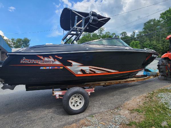Slide: The Image of 2014 Monterey 234 Super Sport boat on a trailer, black with orange graphics. - 1