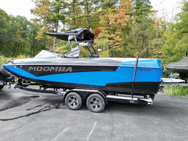 Slide: The Image of 2019 Moomba Makai boat on a trailer, blue and black, parked outdoors. - 2