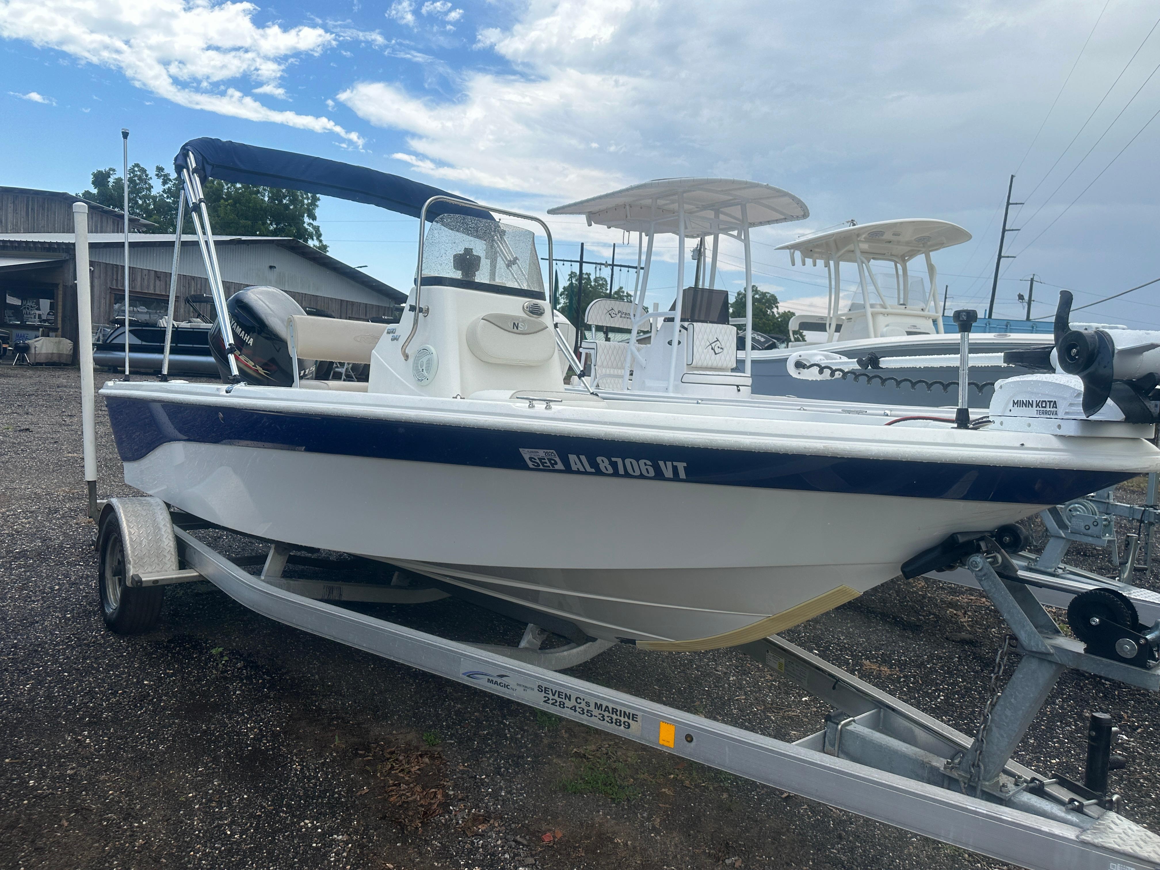 Slide: The Image of 2015 NauticStar 1810 NauticBay boat on trailer, parked outdoors under cloudy sky. - 14