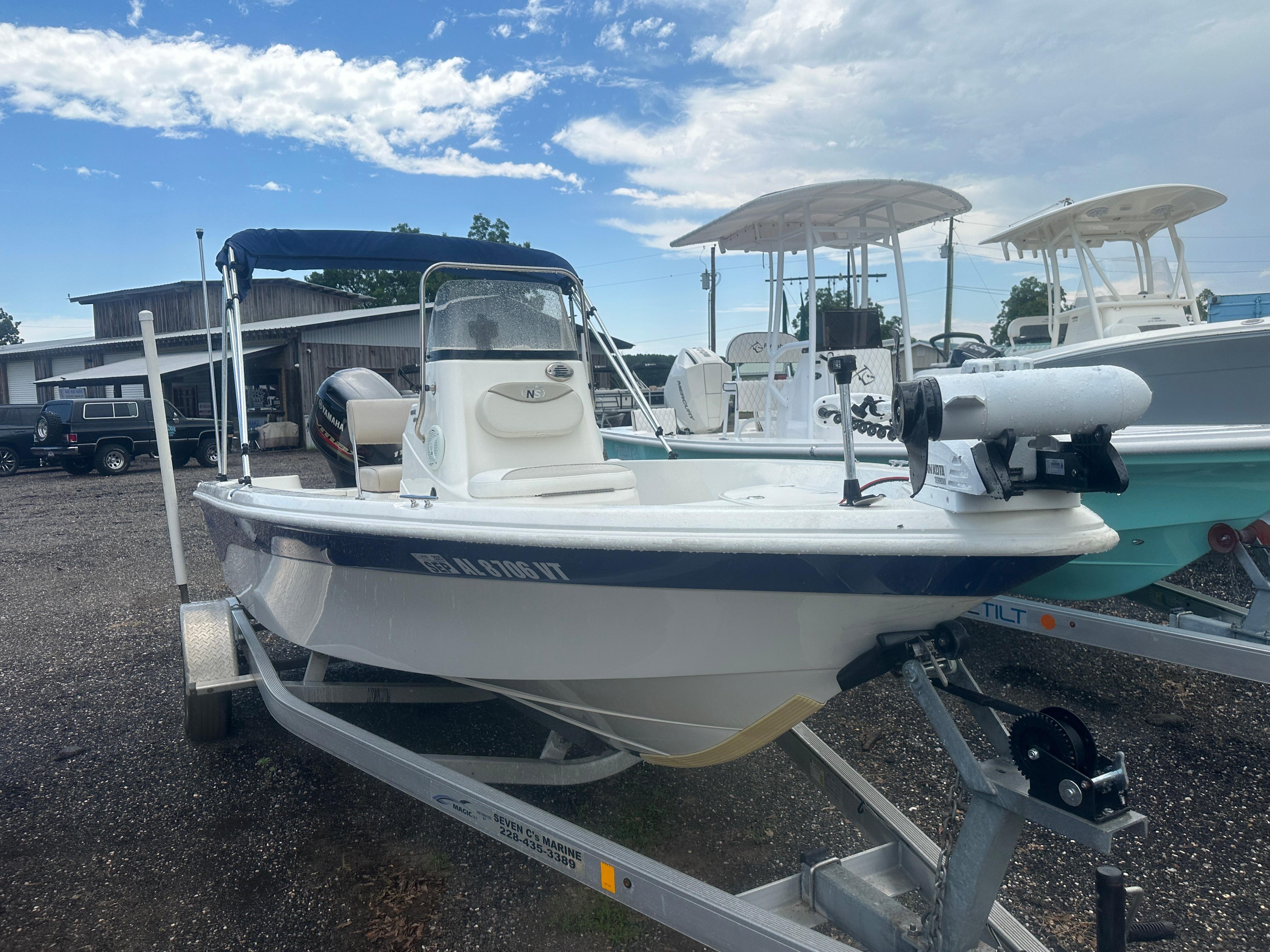 Slide: The Image of 2015 NauticStar 1810 NauticBay boat on trailer, parked outdoors under cloudy sky. - 15