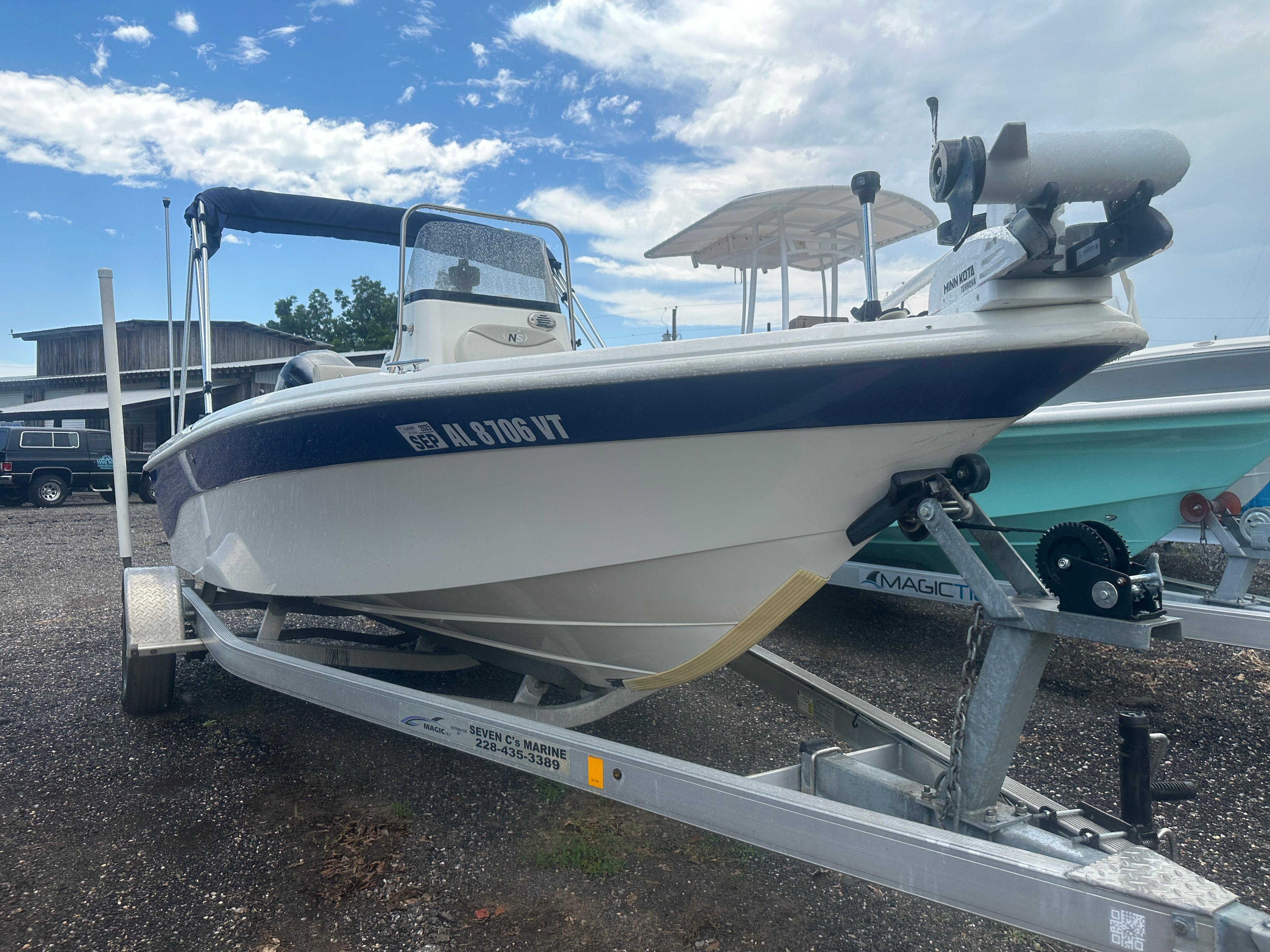 Slide: The Image of 2015 NauticStar 1810 NauticBay boat on trailer, parked outdoors under a cloudy sky. - 16