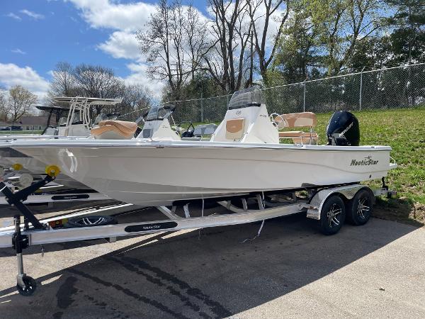 Slide: The Image of 2023 NauticStar 215 XTS boat on a trailer, parked outdoors on a sunny day. - 0