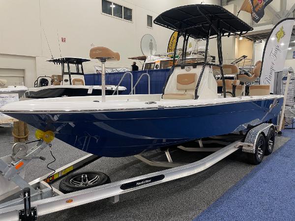 Slide: The Image of 2023 NauticStar 227 XTS boat with blue hull on display indoors. - 0