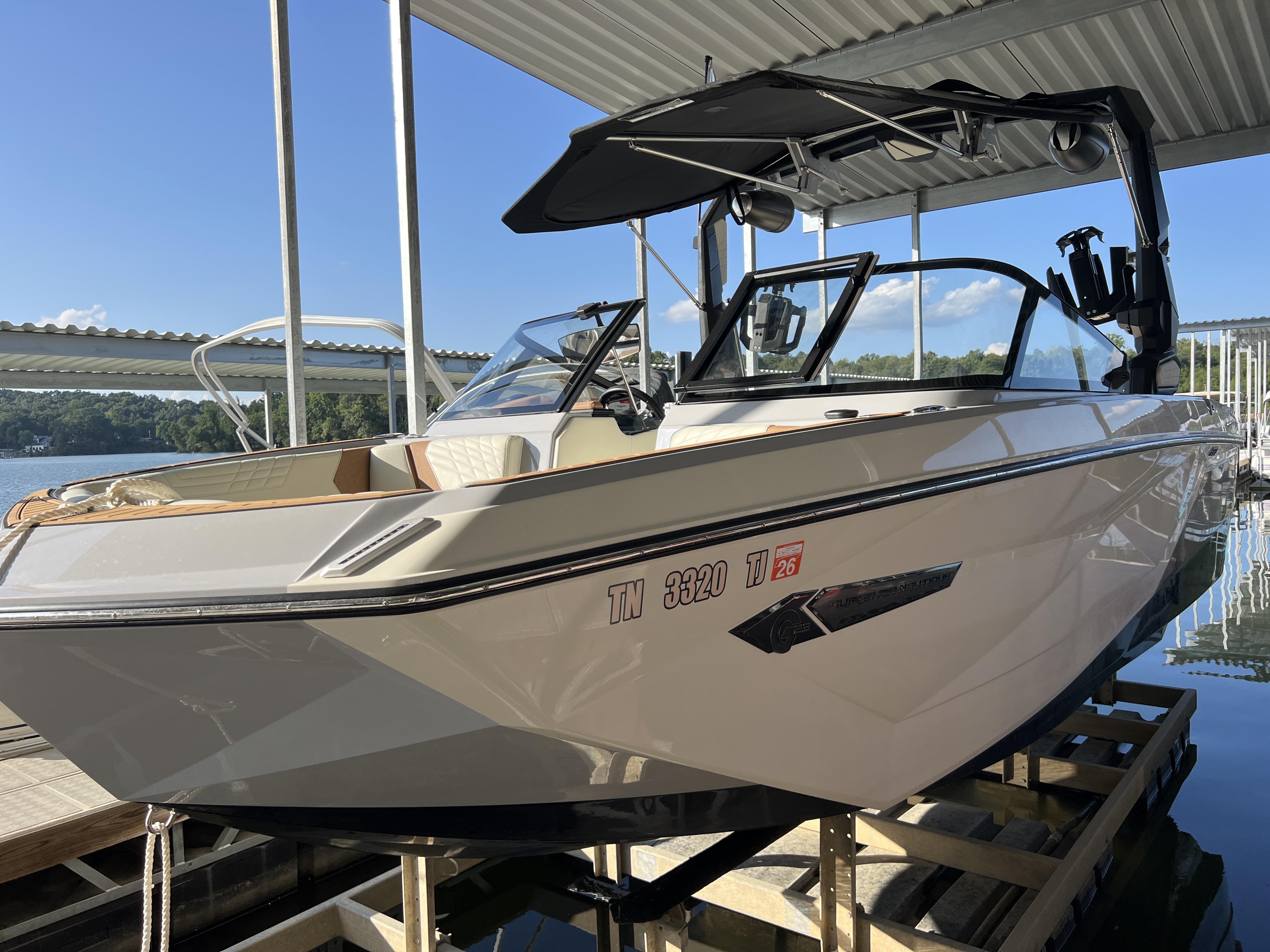 Slide: The Image of 2023 Nautique G23 boat docked under a covered marina. - 19