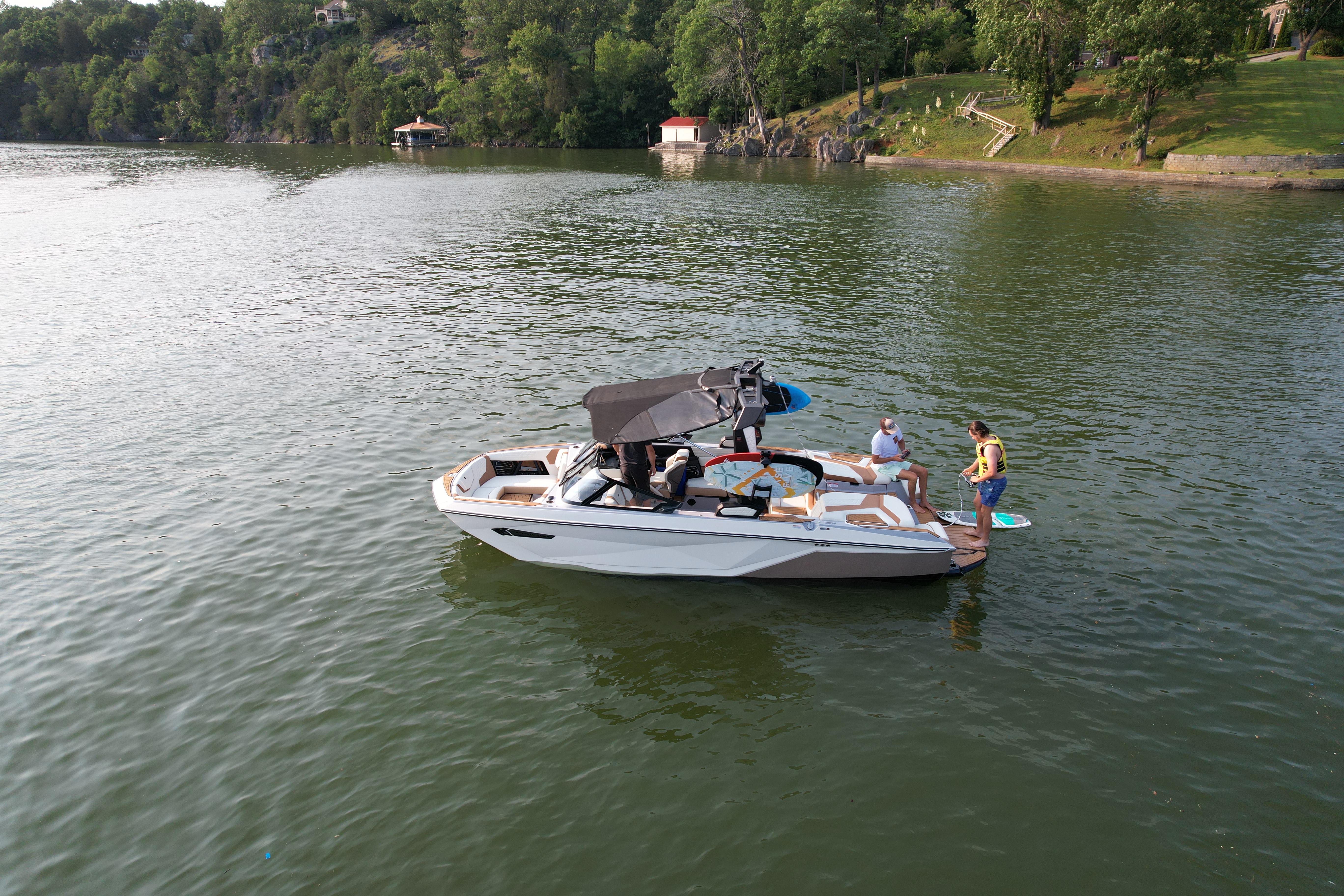 Slide: The Image of 2023 Nautique G23 boat on a lake with people preparing for water activities. - 21