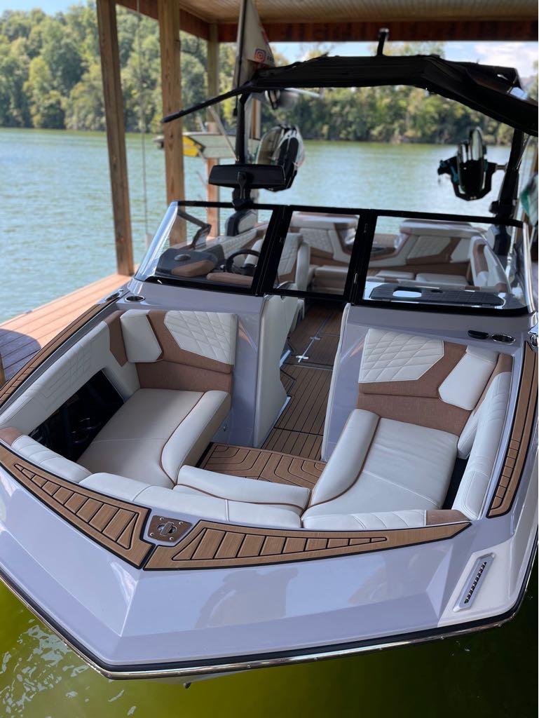 Slide: The Image of 2023 Nautique G23 boat with luxurious seating docked on a serene lake. - 25