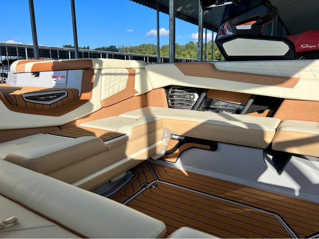 Slide: The Image of Interior of 2023 Nautique G23 boat with tan and white seating, docked under a canopy. - 26