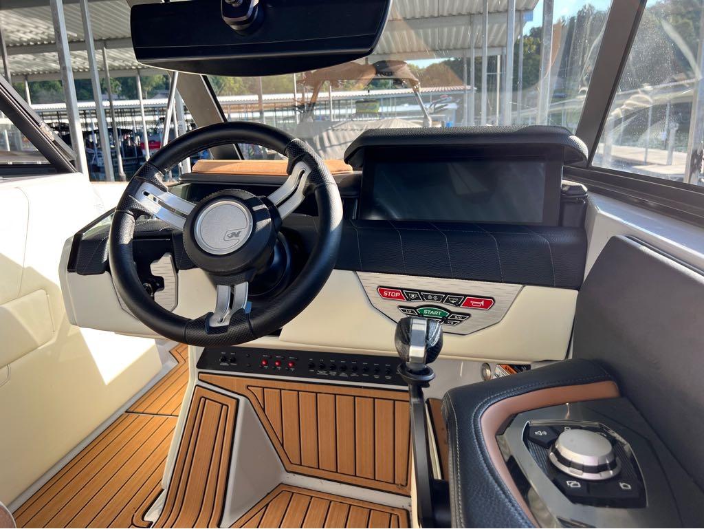 Slide: The Image of 2023 Nautique G23 boat dashboard with steering wheel, touchscreen, and control panel. - 33