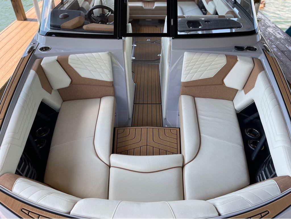 Slide: The Image of 2023 Nautique G23 boat interior with luxurious white and tan seating, wood flooring, and modern design. - 34