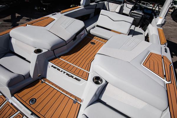 Slide: The Image of 2022 Nautique G25 boat interior with teak flooring and white cushioned seating. - 13
