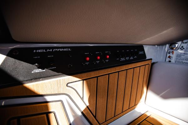 Slide: The Image of 2022 Nautique G25 helm panel with wooden accents and control switches. - 19
