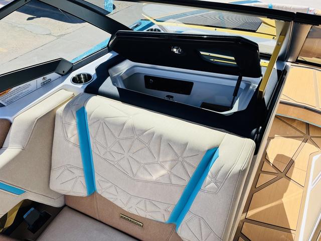Slide: The Image of 2024 Nautique G25 Paragon boat interior with beige and blue seating, cup holder, and storage compartment. - 22