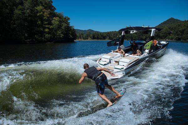Slide: The Image of 2023 Nautique Super Air Nautique G23 Paragon towing a wakeboarder on a scenic lake. - 23