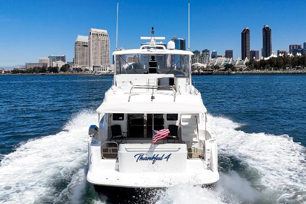 Slide: The Image of 2008 Navigator 62 Pilothouse yacht cruising near city skyline, American flag waving. - 1