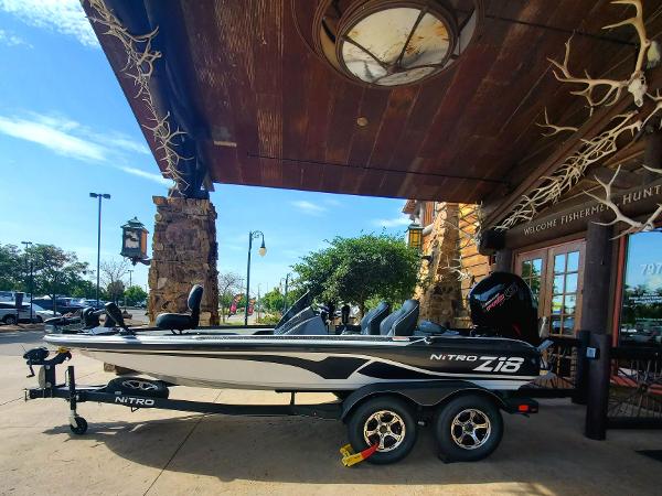 Slide: The Image of 2024 Nitro Z18 boat parked outside a rustic building under a clear blue sky. - 2