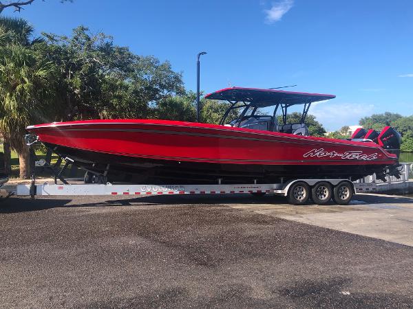 Slide: The Image of 2022 Nor-Tech 390 Sport Center Console boat on a trailer, vibrant red color. - 0
