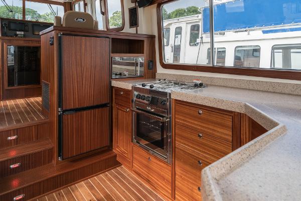 Slide: The Image of Modern kitchen in 2025 Nordic Tug 40 boat with wood cabinetry and stainless steel appliances. - 7
