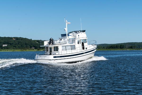 Slide: The Image of 2025 Nordic Tug 44 cruising on a lake with scenic background. - 10