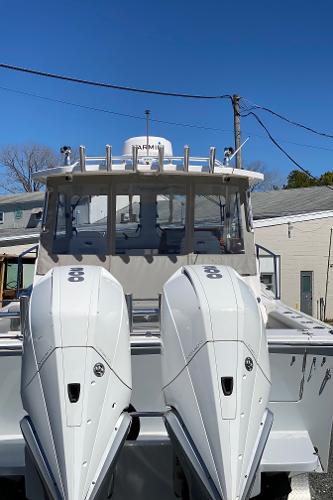 Slide: The Image of 2021 NorthCoast 315 HT boat with dual outboard engines, docked under a clear blue sky. - 21