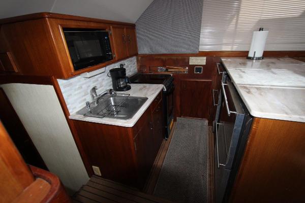 Slide: The Image of 1990 Ocean Yachts 48 Super Sport kitchen with sink, stove, microwave, and wooden cabinetry. - 18
