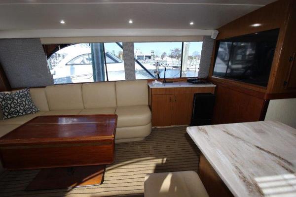 Slide: The Image of 1990 Ocean Yachts 48 Super Sport interior with beige seating, wooden table, and large windows. - 9