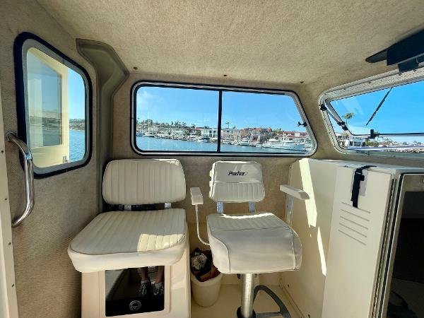Slide: The Image of Interior of 2008 Parker 2520 DV boat with white seating and marina view. - 13