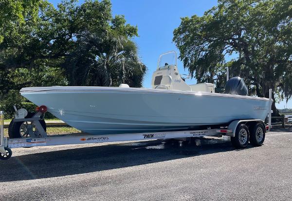 Slide: The Image of 2024 Pathfinder 2200 TRS boat on a trailer, parked outdoors under trees. - 0