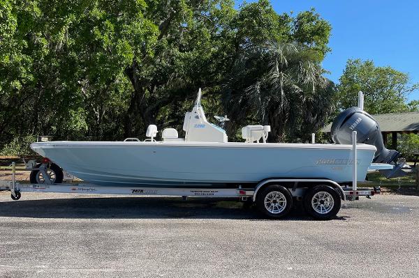 Slide: The Image of 2024 Pathfinder 2200 TRS boat on a trailer, parked outdoors with trees in the background. - 1