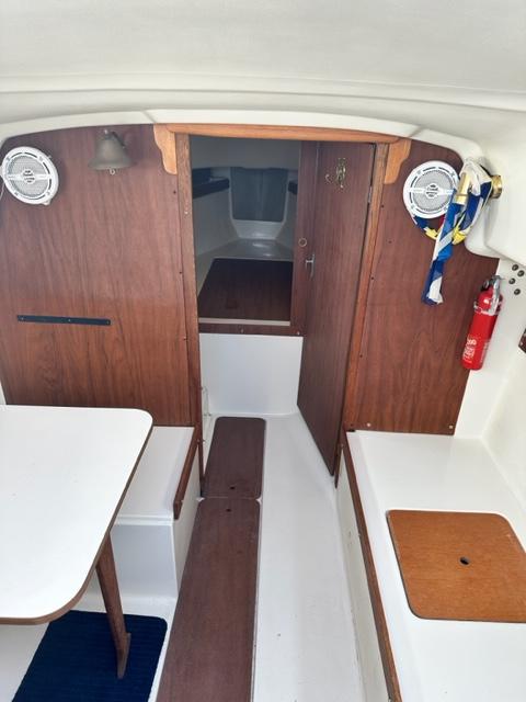 Slide: The Image of Interior of a 1978 Pearson 26 sailboat with wooden cabinetry and white seating. - 14